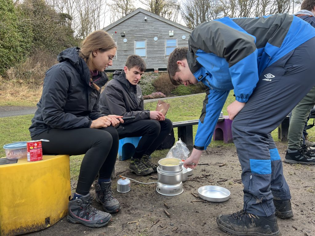 young people cooking on a trangia