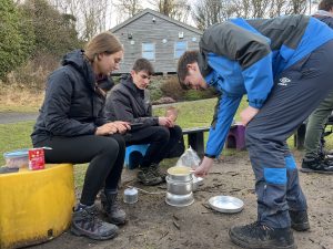 young people cooking on a trangia
